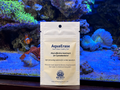 Front of the AquaErase pouch standing in front of a lit reef aquarium with a clownfish and corals